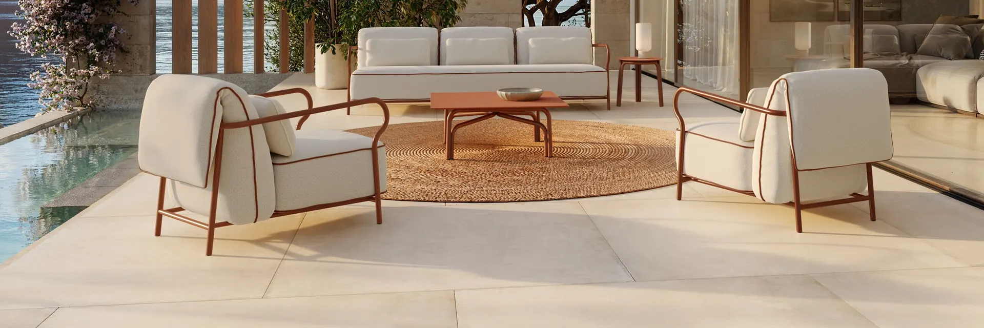 Unopiù Salò sofas and armchairs around low tables in the paved courtyard of a modern villa with glass walls