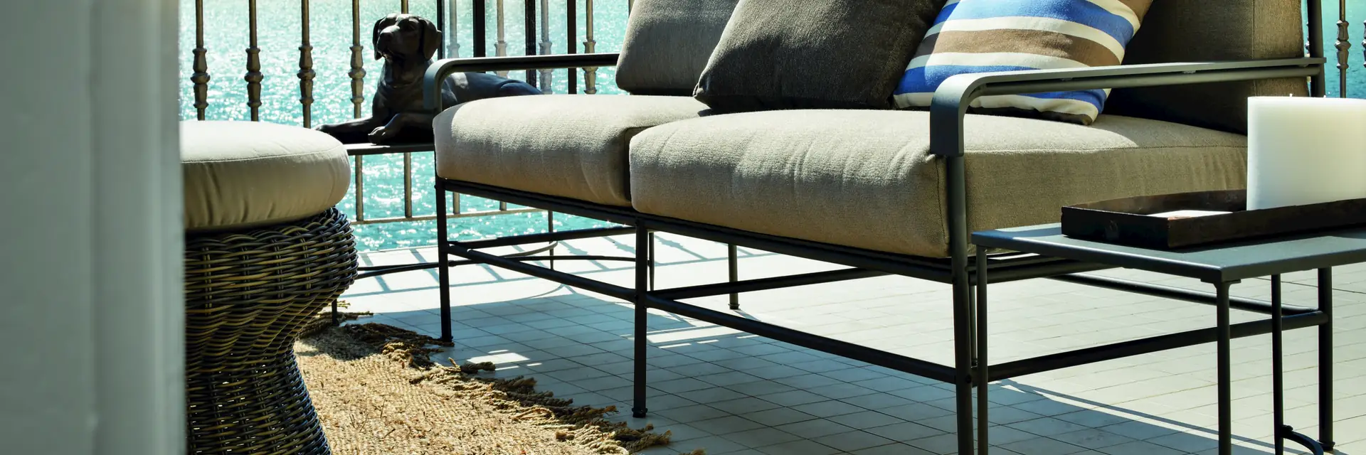 Unopiù Toscana iron-framed sofa with striped cushions on a terrace beside a lake