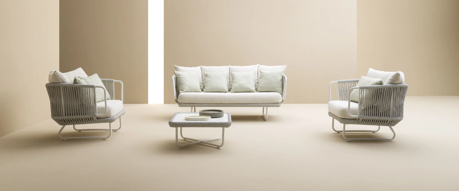 Varaschin Babylon sofa and two woven armchairs around low tables in a bright porch with tall pale columns