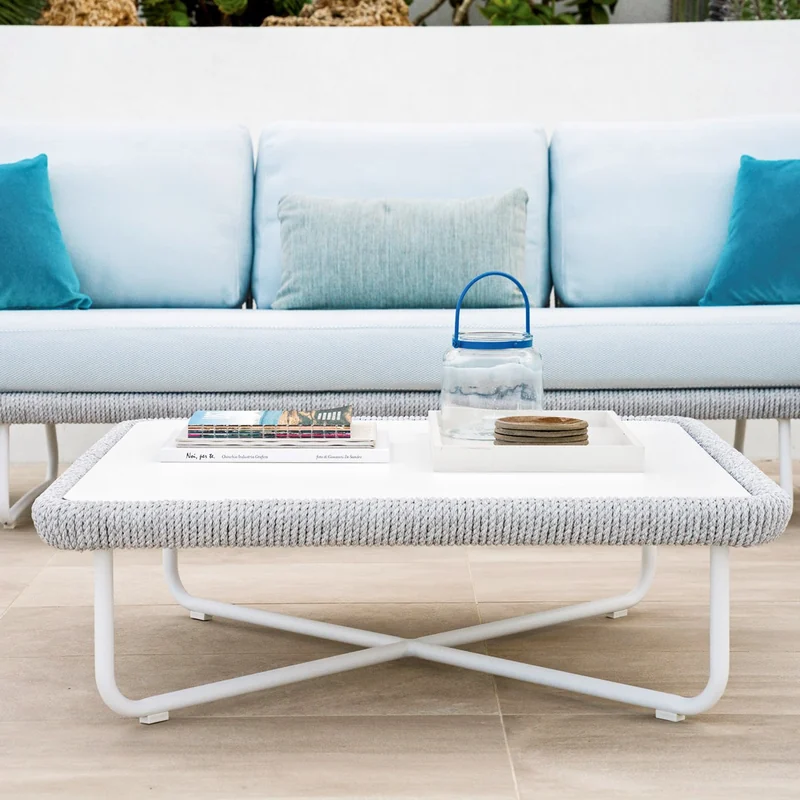 Varaschin Babylon sofa with a white rope frame, pale seat and turquoise cushions, behind a white coffee table