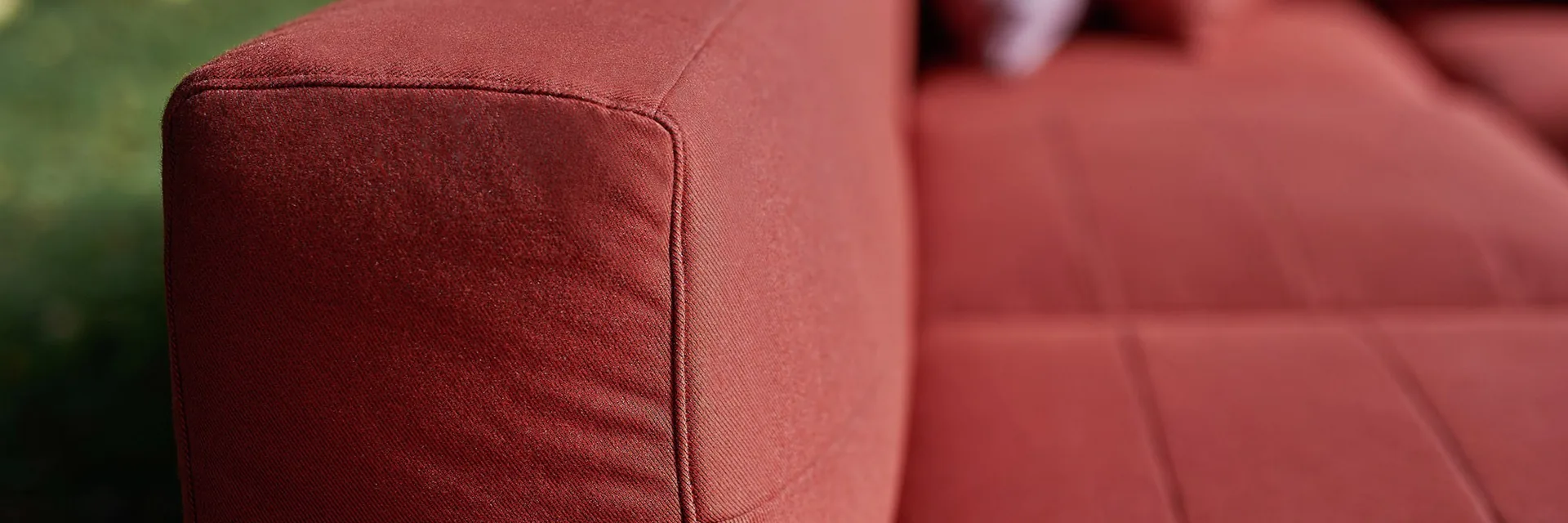 Close view of the red seat and armrest cushions of a Varaschin Barcode sectional sofa on a lawn