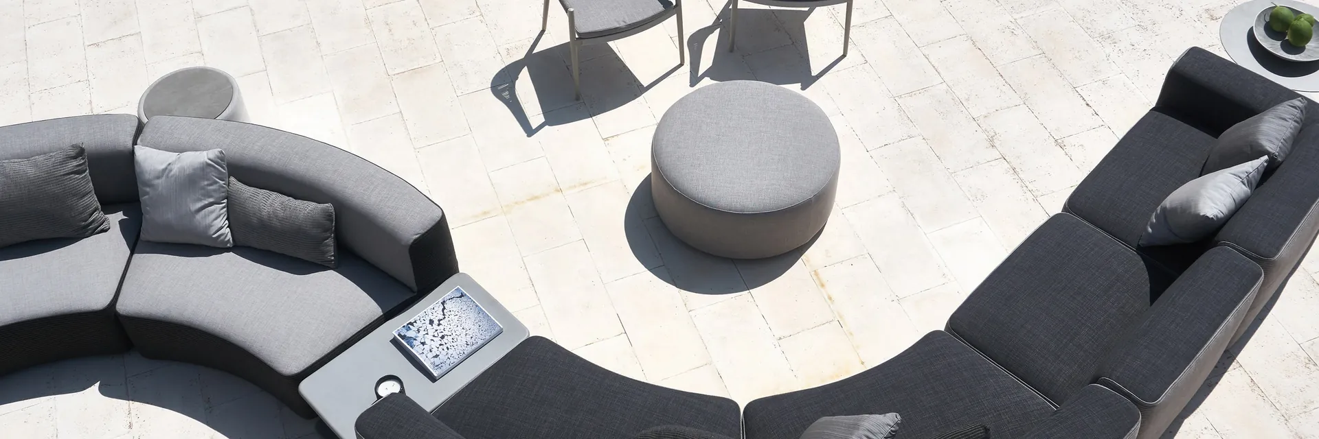 Varaschin Belt curved modular sofa in dark fabric with a round pouf and two armchairs, seen from above on a stone terrace