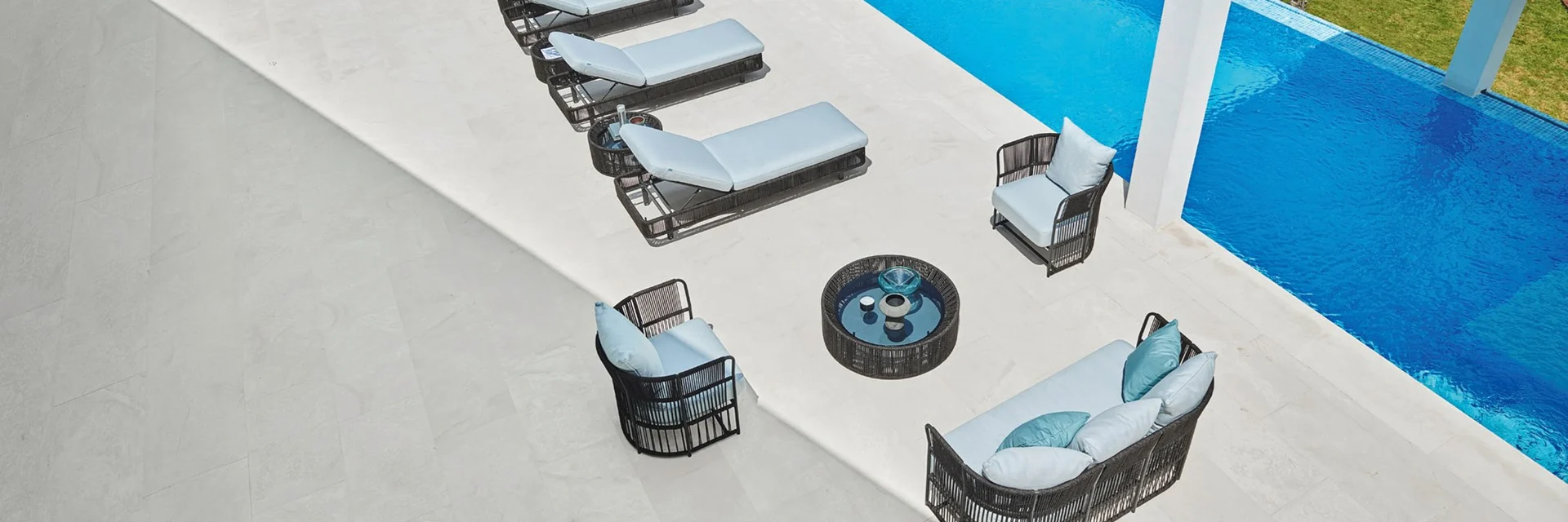 Varaschin Tibidabo armchairs around a low table and a row of sun loungers beside a pool, seen from above